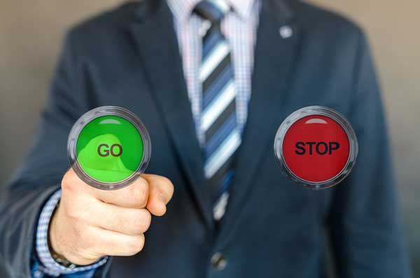 Man in suit pressing GO button next to STOP button