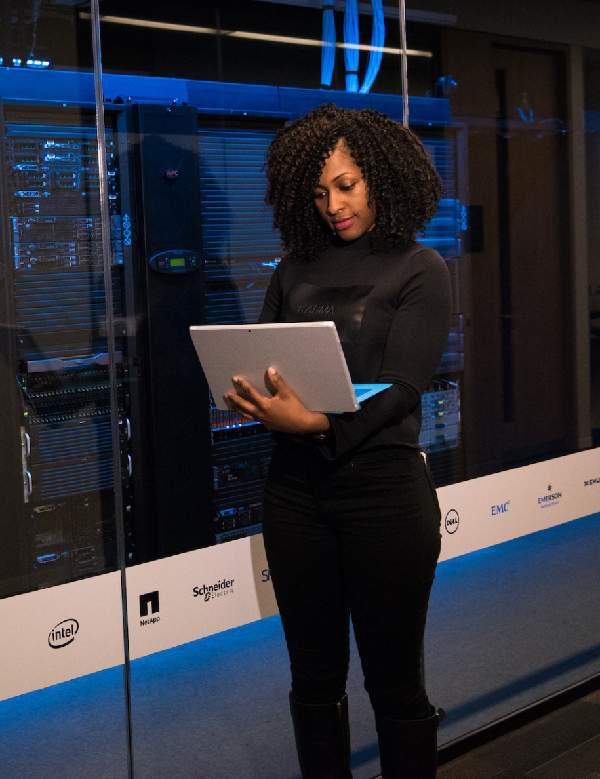 A woman monitoring the statis of servers from a laptop.