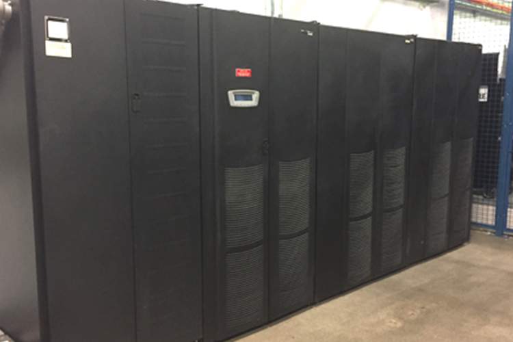 A series of large, black uninterruptible power supply (UPS) units inside a data center.