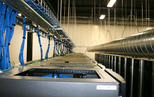 Organized blue cables above server racks in a data center.